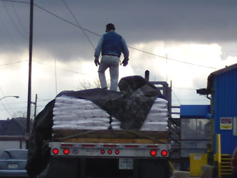 A trucker tarps skid loads of packaged salt to be distributed locally at the Cargill Salt Company located on Jones Island.