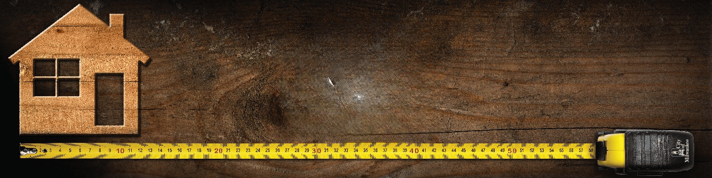 A wooden plank with a home and tape measure.
