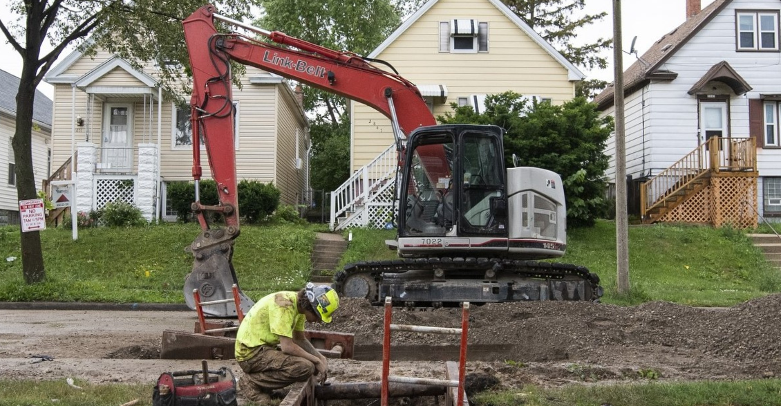 Close-up of a worker’s hands tightening a pipe fitting during a lead service line replacement