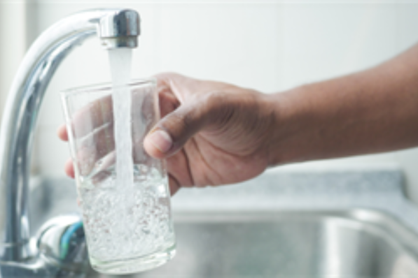 an image of a person's hand filling up a glass of water under their faucet