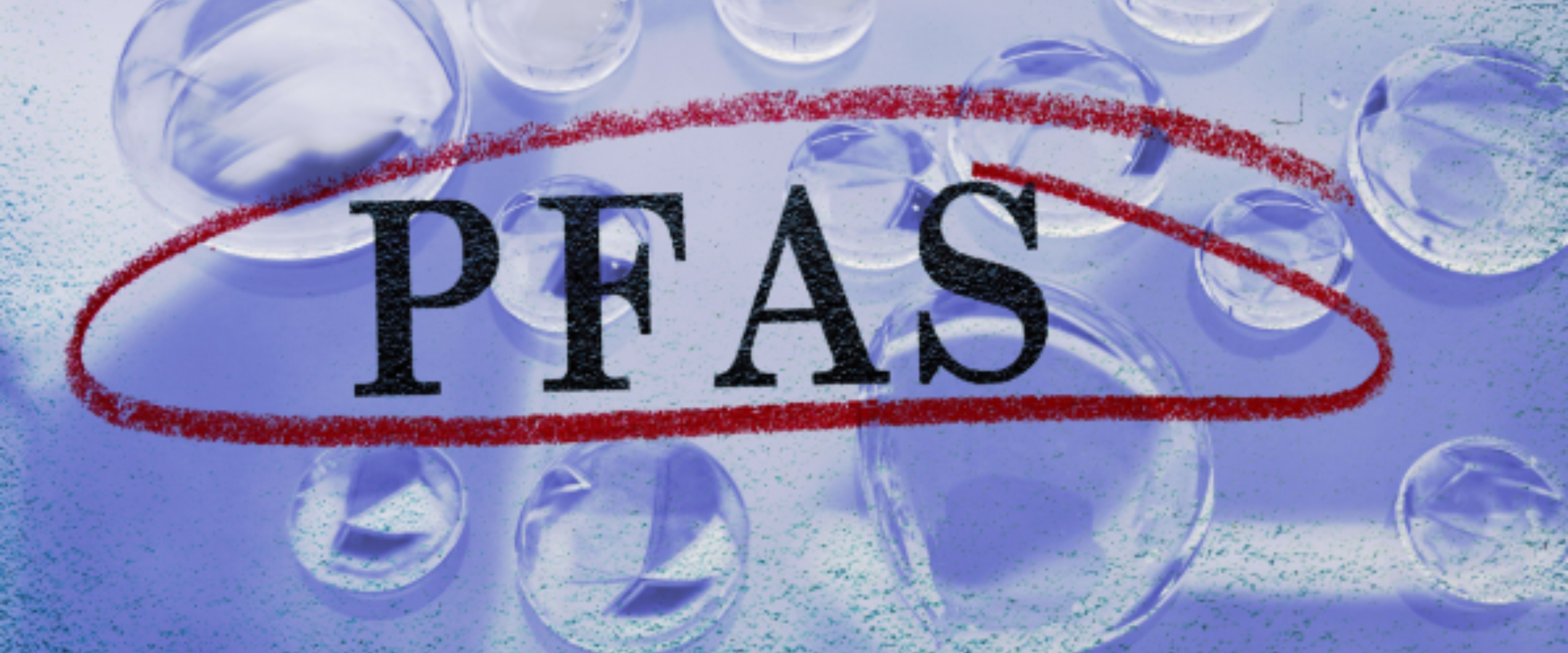 Close-up of the letters 'PFAS' printed on a surface, circled in red, with water droplets in the background.