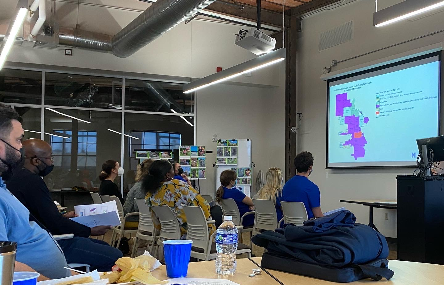 A group of people review a PowerPoint slide in a large conference room