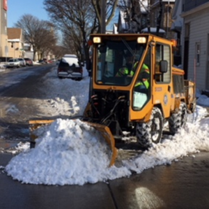 Image of a City of Milwaukee trackless truck cleaning snow on a residential street.
